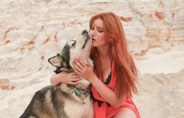 Grappig beste vrienden concept. Gelukkige jonge vrouwelijke persoon loopt in de woestijn met grote hond Malamute buitenshuis — Stockfoto