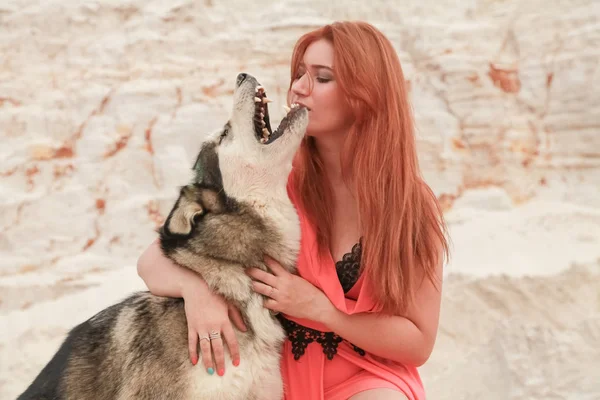 Grappig beste vrienden concept. Gelukkige jonge vrouwelijke persoon loopt in de woestijn met grote hond Malamute buitenshuis — Stockfoto