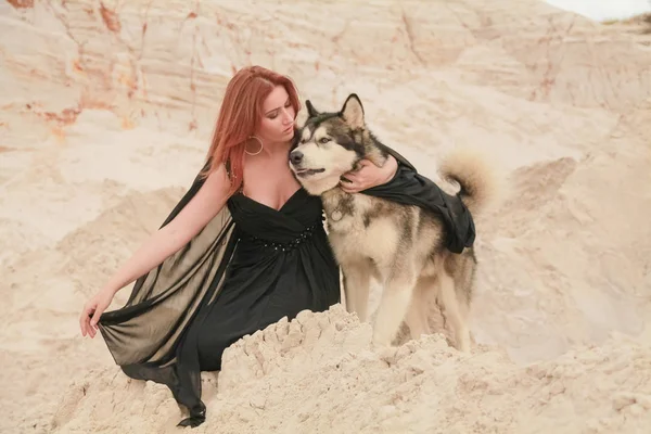 Grappig beste vrienden concept. Gelukkige jonge vrouwelijke persoon loopt in de woestijn met grote hond Malamute buitenshuis — Stockfoto