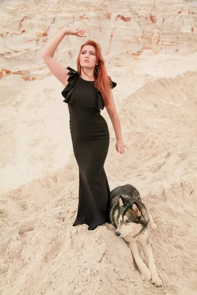 Concepto divertido de los mejores amigos. Feliz joven mujer camina en el desierto con el perro grande malamute al aire libre —  Fotos de Stock