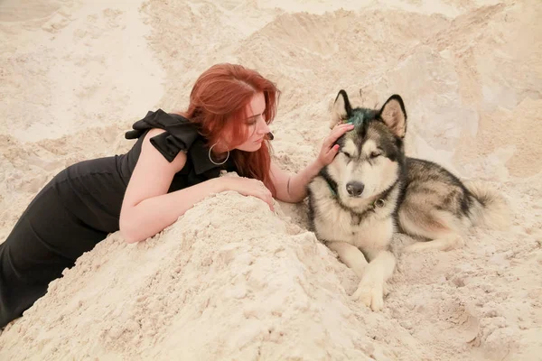 Grappig beste vrienden concept. Gelukkige jonge vrouwelijke persoon loopt in de woestijn met grote hond Malamute buitenshuis — Stockfoto