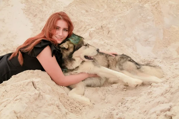 Αστεία ιδέα των καλύτερων φίλων. Ευτυχισμένο νεαρό θηλυκό πρόσωπο περπατά στην έρημο με μεγάλο σκύλο Μαλαμούτ σε εξωτερικούς χώρους — Φωτογραφία Αρχείου