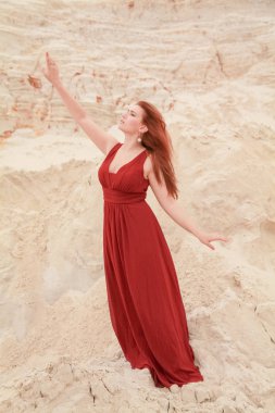 Genç güzel artı boyutu kırmızı uzun elbiseli beyaz kadın kum ile çöl manzara poz.