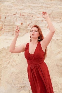 Genç güzel artı boyutu kırmızı uzun elbiseli beyaz kadın kum ile çöl manzara poz.