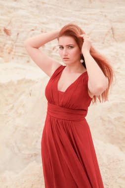 Genç güzel artı boyutu kırmızı uzun elbiseli beyaz kadın kum ile çöl manzara poz.