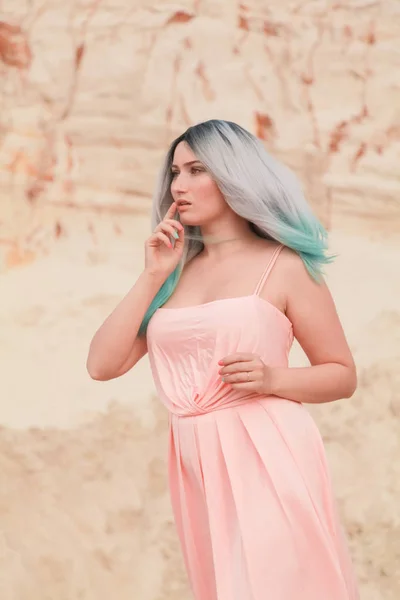 Giovane bella donna caucasica in abito lungo rosa in posa nel paesaggio desertico con sabbia . — Foto Stock