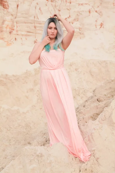 젊은 아름다운 백인 여성 에 긴 분홍색 드레스 포즈 에 사막 풍경 와 모래. — 스톡 사진