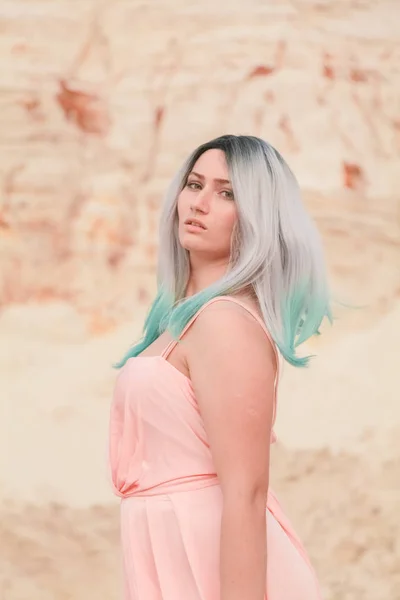 Mulher branca bonita nova no vestido rosa longo posando na paisagem do deserto com areia . — Fotografia de Stock