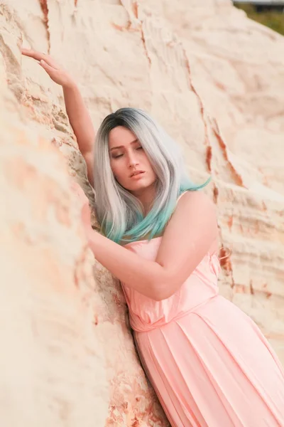 Jeune belle femme caucasienne en robe rose longue posant dans un paysage désertique avec du sable . — Photo