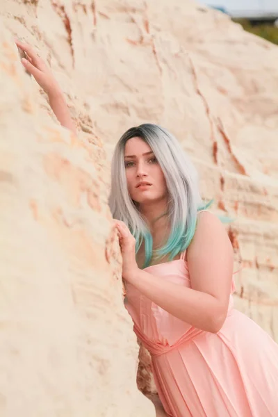 Mulher branca bonita nova no vestido rosa longo posando na paisagem do deserto com areia . — Fotografia de Stock