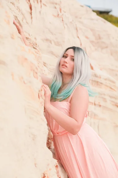 Young beautiful Caucasian woman in long pink dress posing in desert landscape with sand. — Stock Photo, Image
