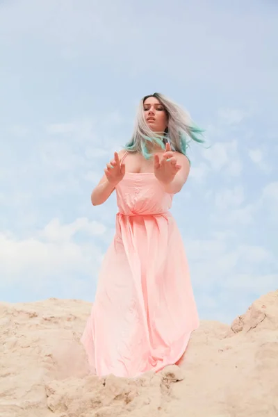 Jeune belle fille caucasienne se tient sur le monticule de sable et regarde vers le bas — Photo