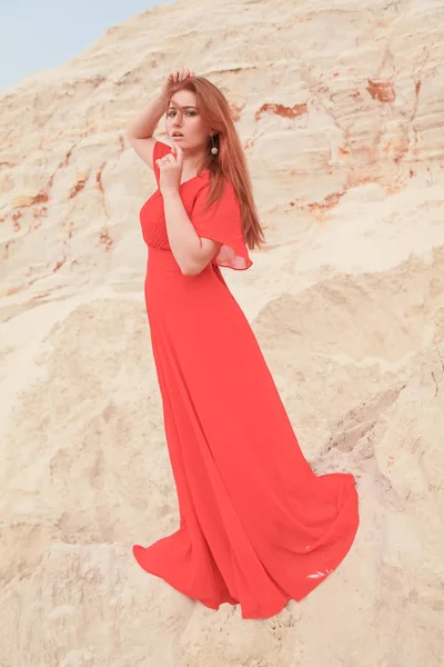 Jeune belle femme caucasienne en tenue longue et lumineuse posant dans un paysage désertique avec du sable . — Photo