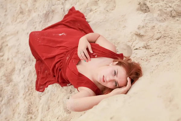 Jeune belle femme caucasienne couchée seule dans un paysage désertique avec du sable . — Photo