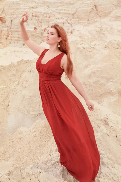 Genç güzel artı boyutu kırmızı uzun elbiseli beyaz kadın kum ile çöl manzara poz.
