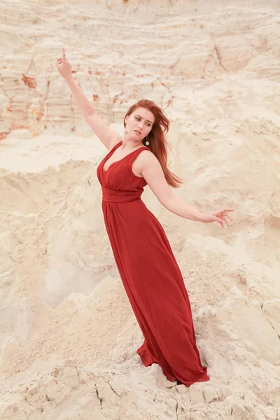 Genç güzel artı boyutu kırmızı uzun elbiseli beyaz kadın kum ile çöl manzara poz.