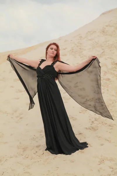 Mulher branca bonita nova no vestido preto do chiffon posando na paisagem do deserto com areia . — Fotografia de Stock
