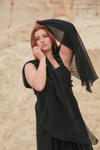Νέα όμορφη καυκάσιος γυναίκα σε μαύρο σιφόν φόρεμα που ποζάρει σε τοπίο έρημο με άμμο. — Φωτογραφία Αρχείου