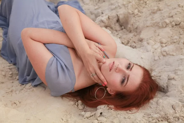 Νέα όμορφη καυκάσιος γυναίκα σε γκρίζο φόρεμα σιφόν που βρίσκεται σε έρημο τοπίο με άμμο. — Φωτογραφία Αρχείου