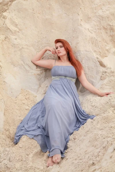 Jeune belle femme caucasienne en robe shiffon du soir posant dans un paysage désertique avec du sable . — Photo