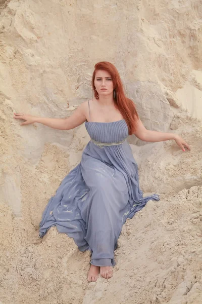 Jeune belle femme caucasienne en robe shiffon du soir posant dans un paysage désertique avec du sable . — Photo