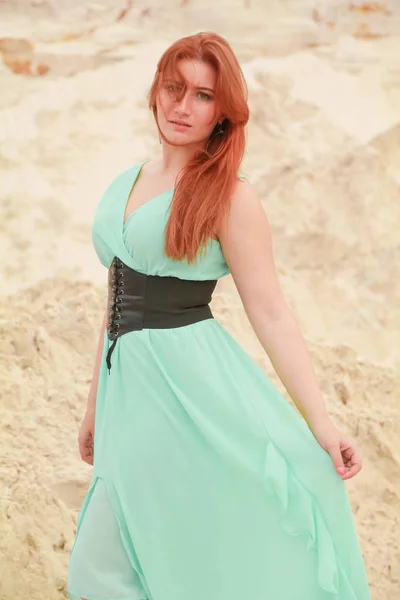 Fiatal gyönyörű kaukázusi nő, kék hosszú műszak ruha pózol a sivatagi táj homokkal. — Stock Fotó