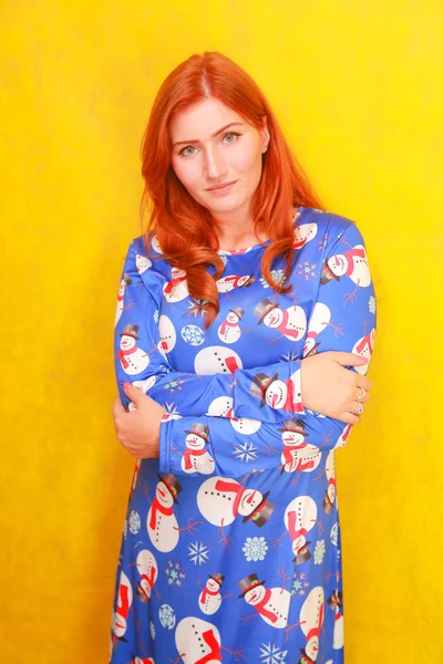 Sarı parlak stüdyo arka plan üzerinde mavi komik noel elbisesi giyen kırmızı saçlı dikkatsiz rüya gibi çekici bayan