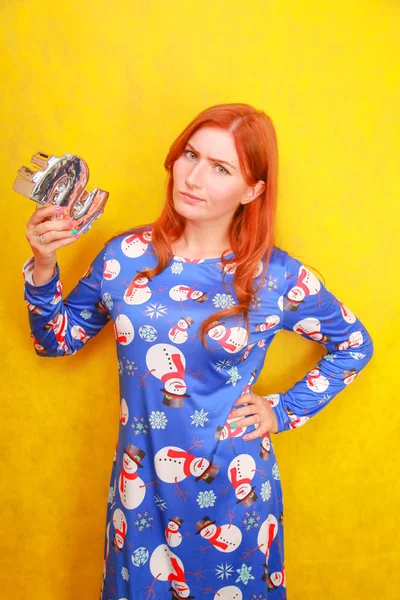 Menina ruiva bonita em azul engraçado vestido de Natal com caixa de dinheiro de moeda no fundo amarelo. mulher se preparando para o ano novo e pronto para comprar presentes e presentes . — Fotografia de Stock