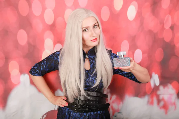 Evinde parfüm şişesi olan güzel genç bir kadın, yakın plan.