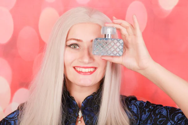 Evinde parfüm şişesi olan güzel genç bir kadın, yakın plan.