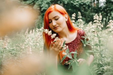 kiraz rengi gece elbisesi kırmızı saçlı kadın şehir parkı arka planda yürüyüş ve yaz keyfini çıkarın