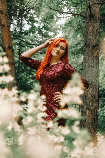 Mulher de cabelos vermelhos em cor de cereja vestido de noite andando no parque da cidade fundo e desfrutar de verão — Fotografia de Stock