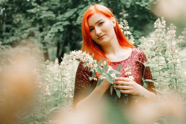 kiraz rengi gece elbisesi kırmızı saçlı kadın şehir parkı arka planda yürüyüş ve yaz keyfini çıkarın