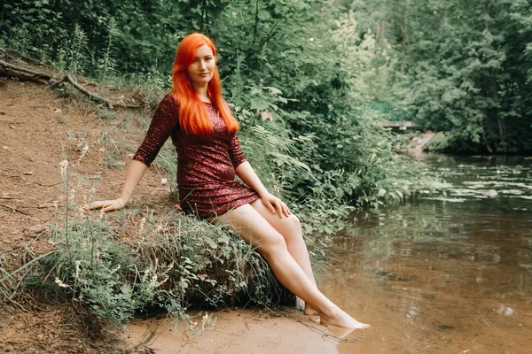 Mulher de cabelos vermelhos em cor de cereja vestido de noite andando no parque da cidade fundo e desfrutar de verão — Fotografia de Stock