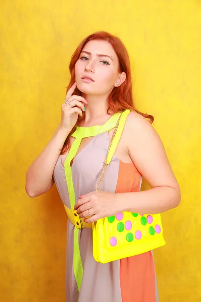 Jolie fille rousse en robe d'été lumineuse avec sac en cuir brillant jaune — Photo