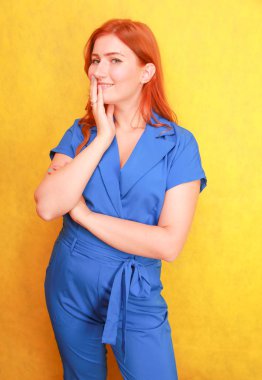 sarı arka plan üzerinde duran mavi moda genel güzel kırmızı saçlı kadın