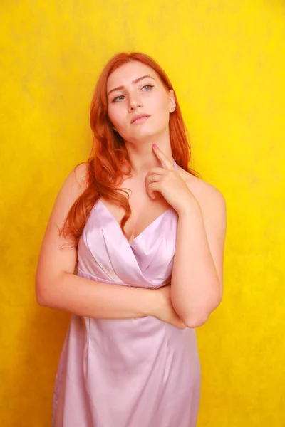 Bonita beleza mulher de cabelo vermelho em vestido de seda rosa no fundo amarelo sozinho. brincalhão plus size menina adulta de cabelos vermelhos . — Fotografia de Stock