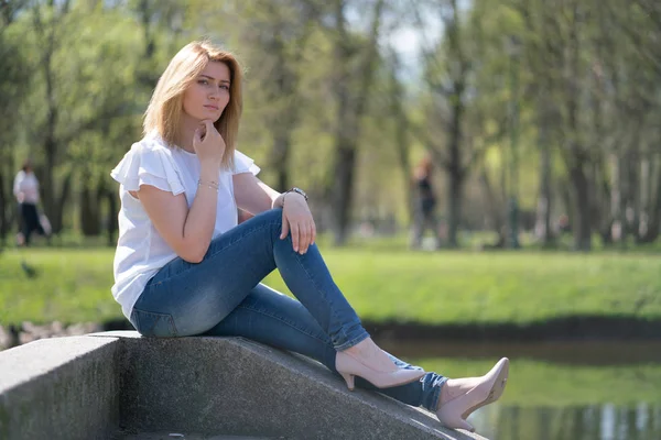 Красива жінка розслабляється, гуляючи в міському парку в джинсах — стокове фото