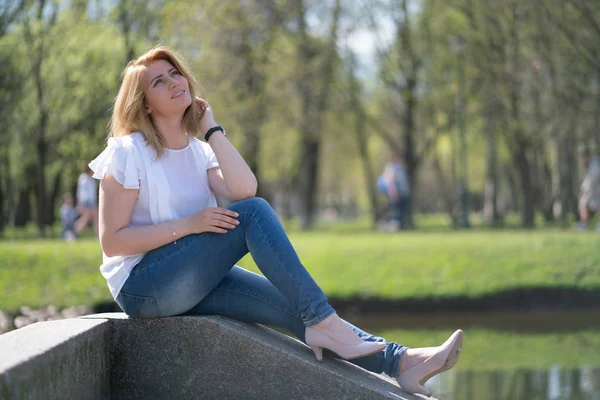 Красивая женщина расслабляется, гуляя в городском парке в джинсовой одежде — стоковое фото