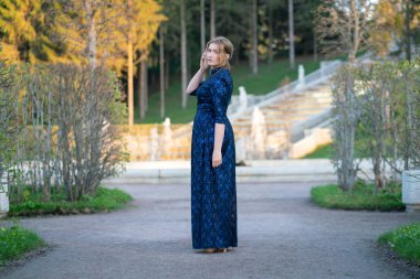 Gün batımında şehirde yürüyen mavi dantel elbiseli bayan