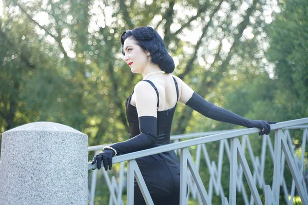 Ретро жінка в класичному платті шпилька на мосту в міському парку — стокове фото
