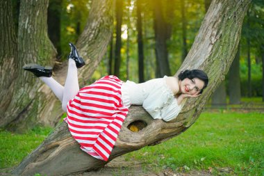 Parkta ağaçla poz veren mutlu bir genç pin up kız yakın çekim