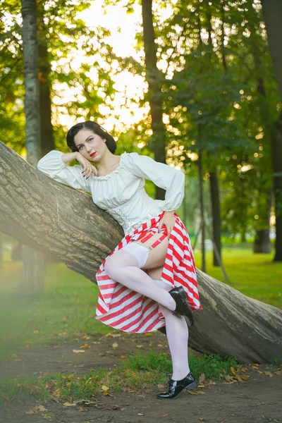 Nahaufnahme eines glücklichen jungen Pin-up-Mädchens, das mit einem Baum im Park posiert — Stockfoto