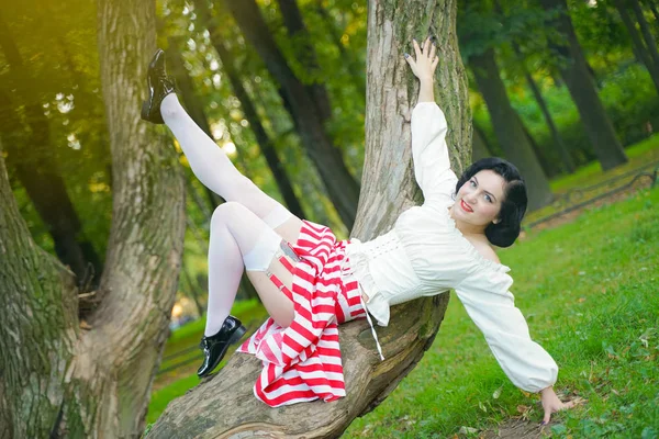 Primo piano di una giovane ragazza felice pin up in posa con l'albero al parco — Foto Stock