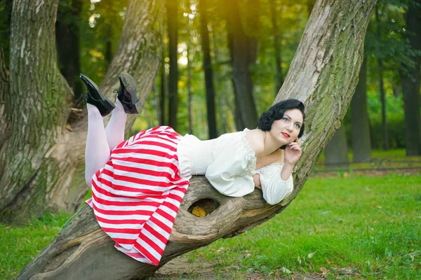 Nahaufnahme eines glücklichen jungen Pin-up-Mädchens, das mit einem Baum im Park posiert — Stockfoto