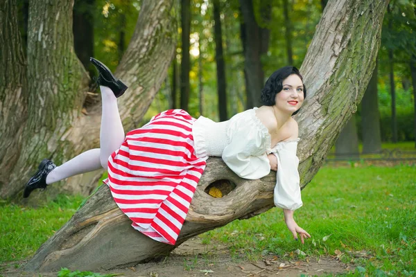 Primo piano di una giovane ragazza felice pin up in posa con l'albero al parco — Foto Stock