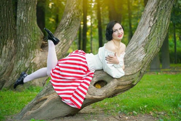 Nahaufnahme eines glücklichen jungen Pin-up-Mädchens, das mit einem Baum im Park posiert — Stockfoto