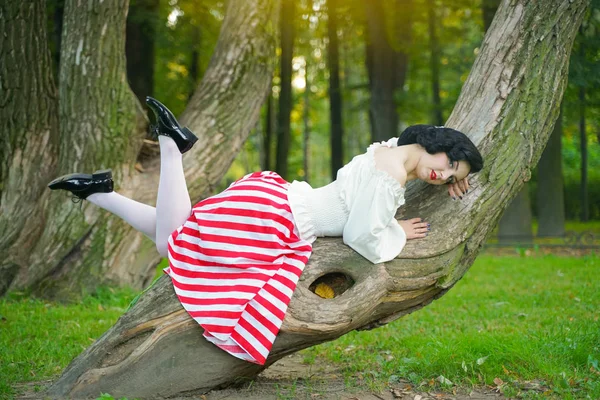 Nahaufnahme eines glücklichen jungen Pin-up-Mädchens, das mit einem Baum im Park posiert — Stockfoto