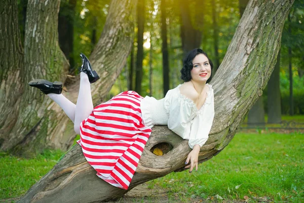 Primo piano di una giovane ragazza felice pin up in posa con l'albero al parco — Foto Stock