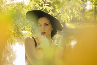 Pin-up makyaj ve saç modeli ile güzel genç kadın yaz şehir parkı poz